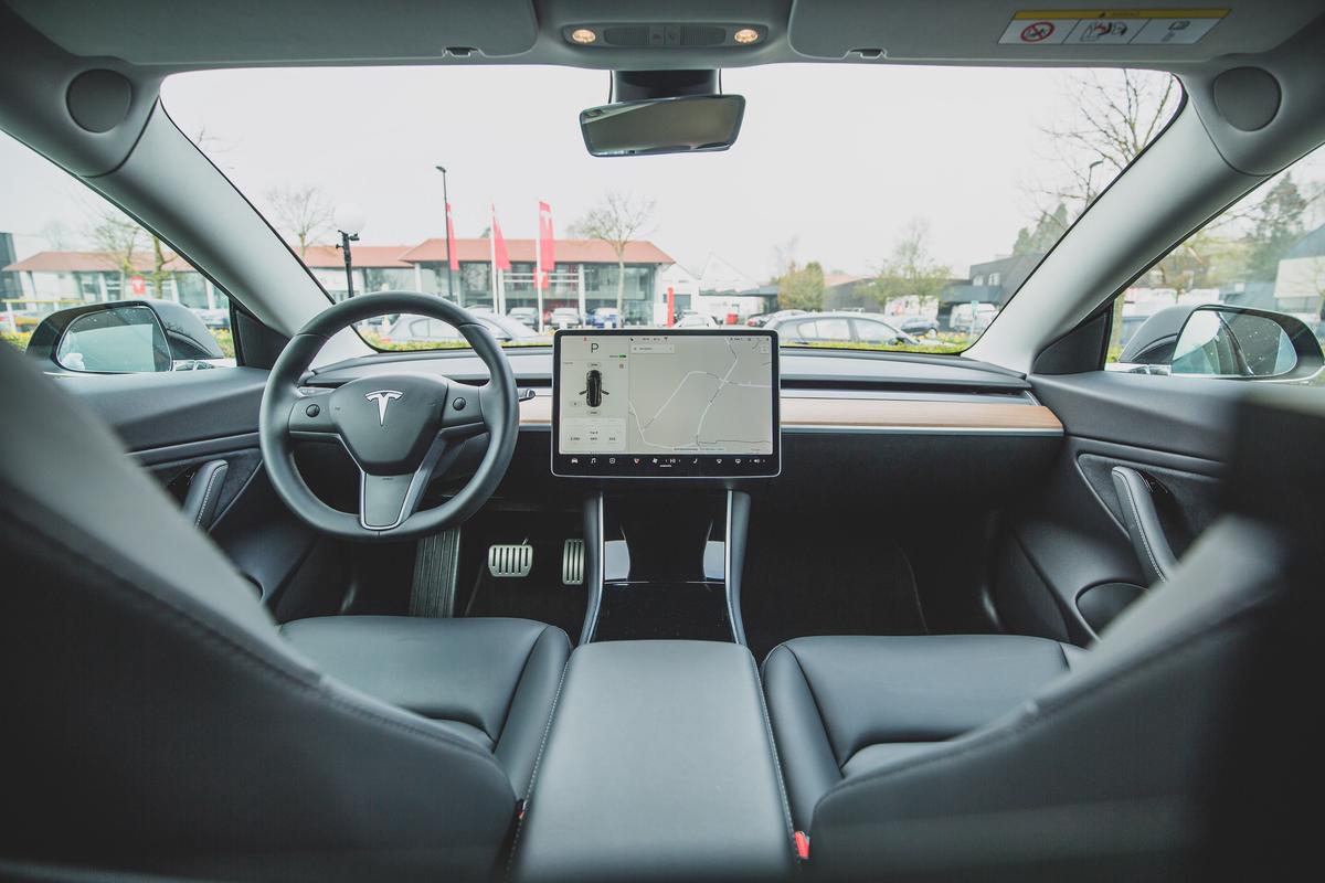 A family sitting in a Tesla car, using the Autopilot feature safely during a family road trip.